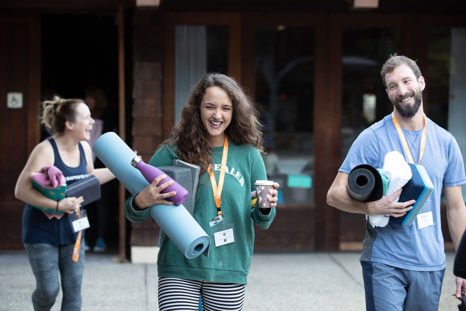 Students carrying yoga mats and water bottles walk together on campus.