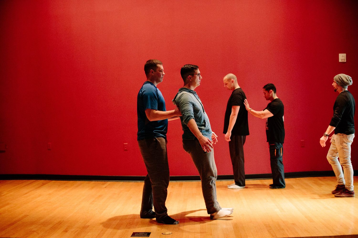 People standing in line against a vibrant red wall during a group activity.