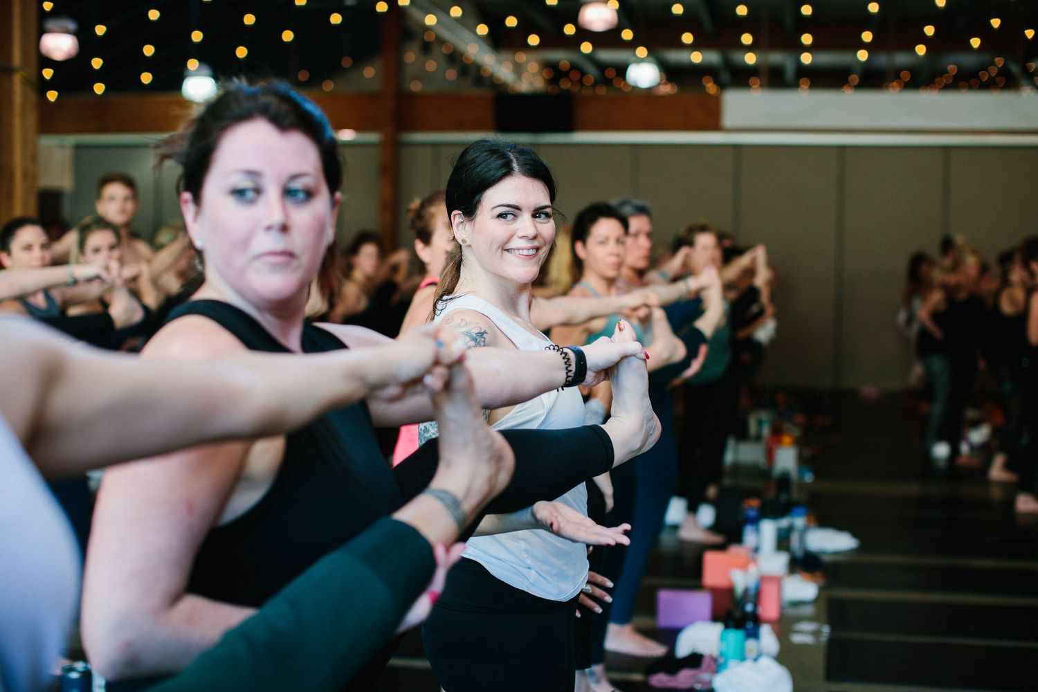 Workshop participants engaged in group discussions and partner exercises in a yoga studio.