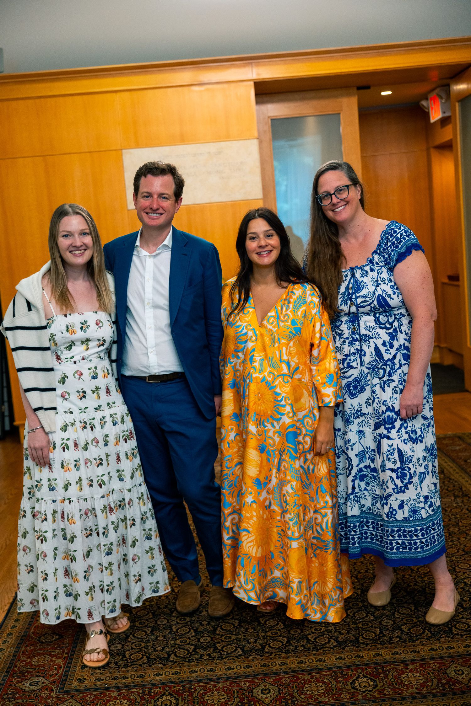 Group wearing colorful summer dresses and formal attire at indoor event.