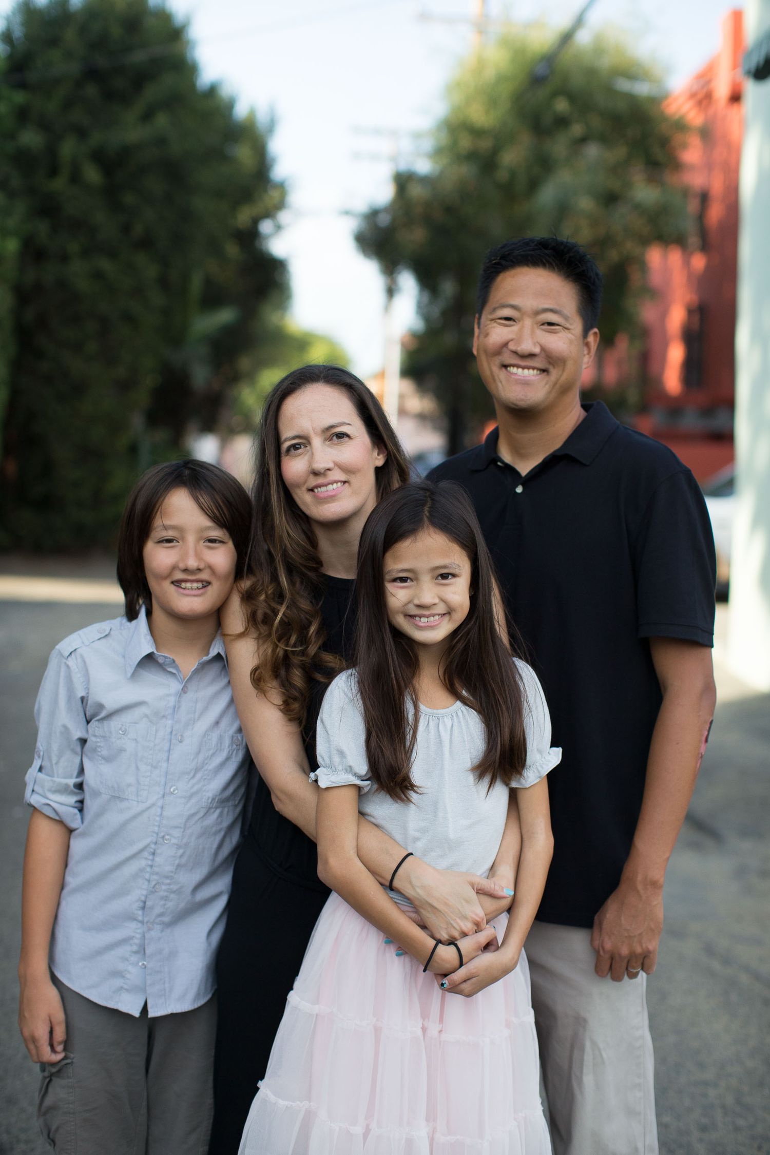 Family group photo outdoors with coordinated casual outfits standing together on a sunny day.
