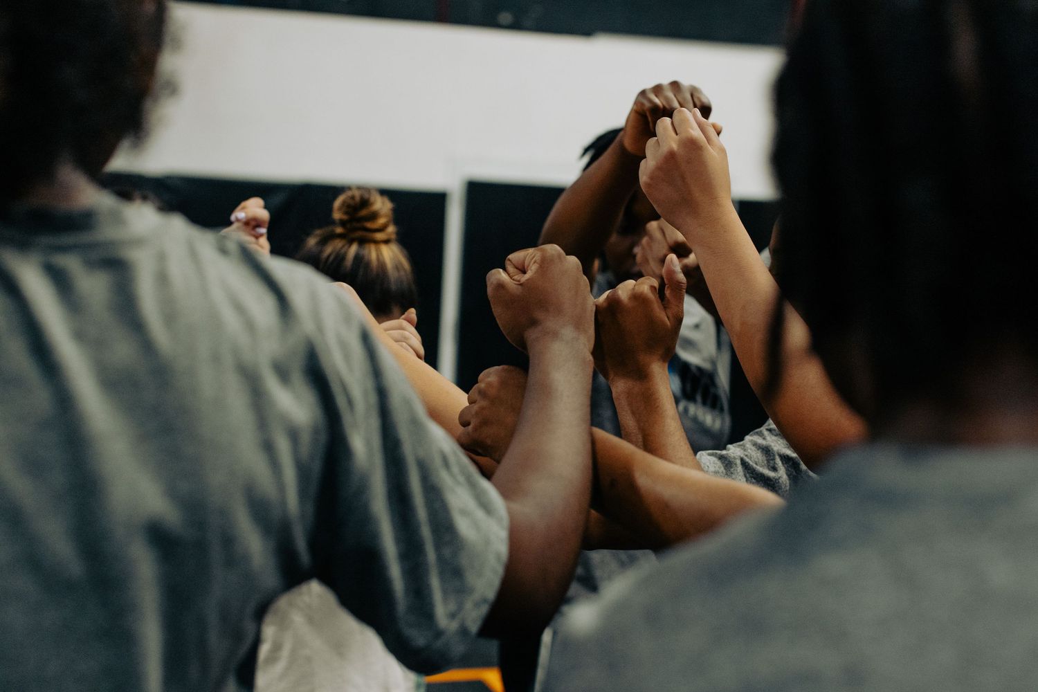 A group raises their hands together in unity during a gathering, symbolizing teamwork and collaboration.