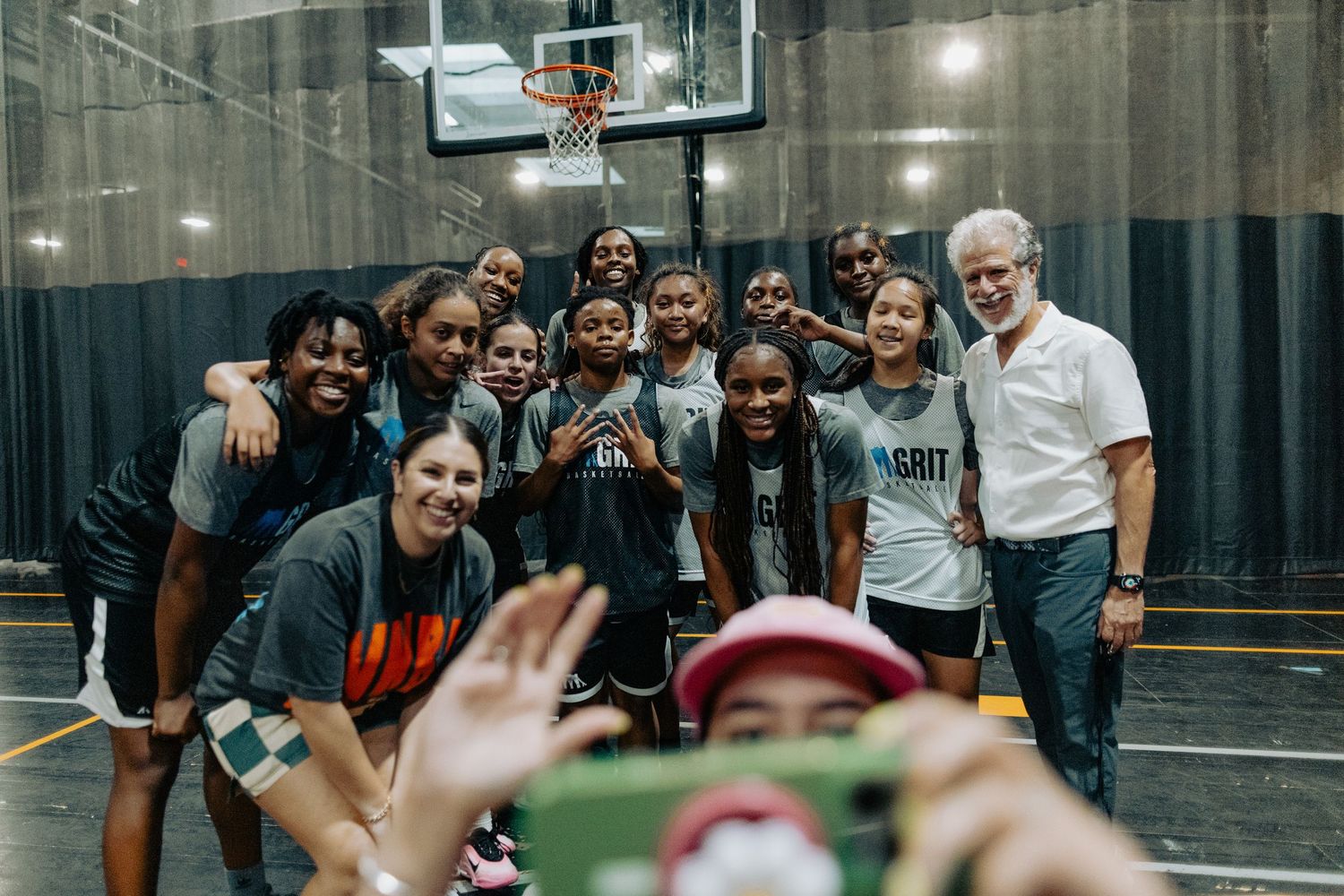 Players and spectators gather around a basketball court during practice session.