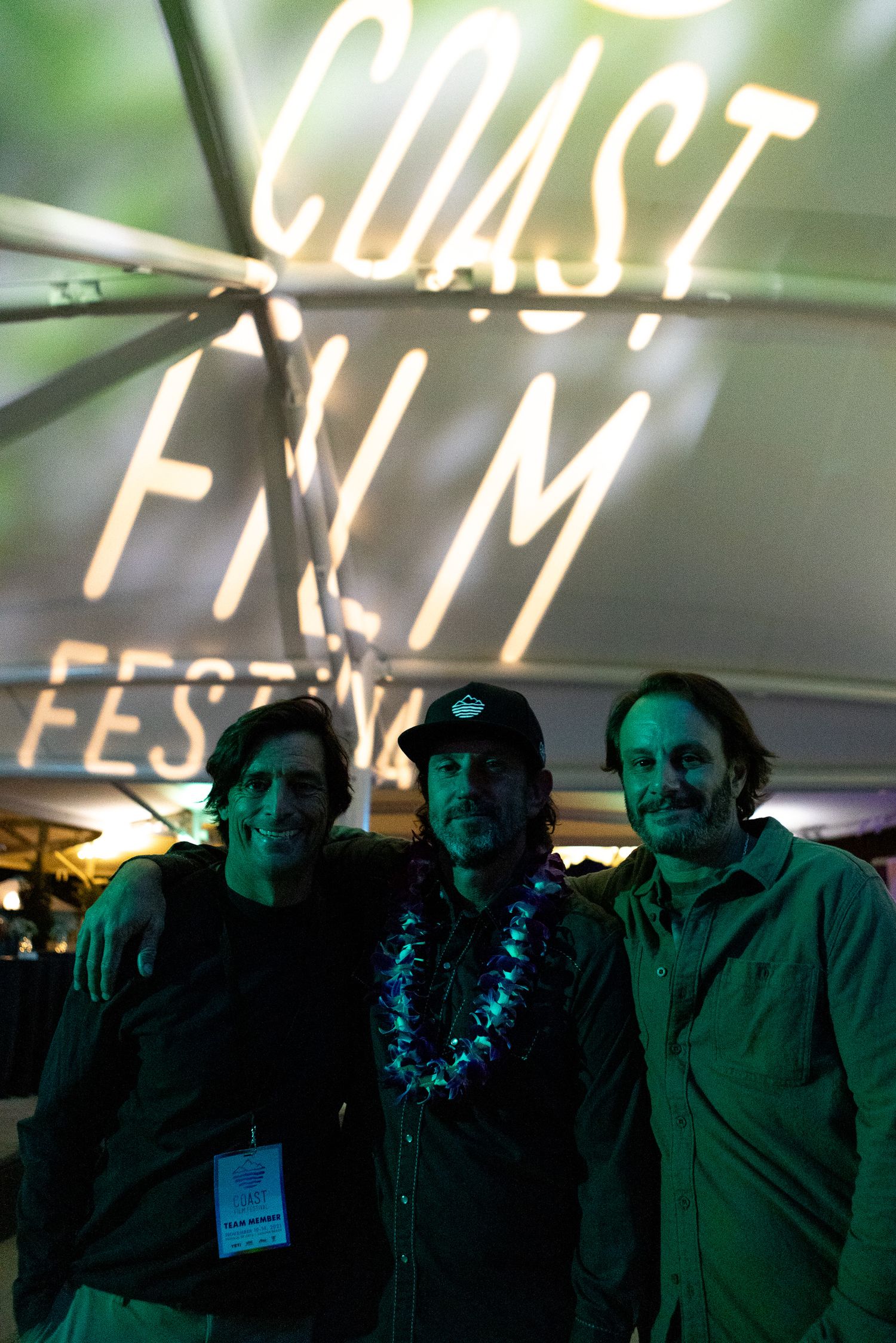 Silhouetted figures standing beneath illuminated signage at a festival or event.