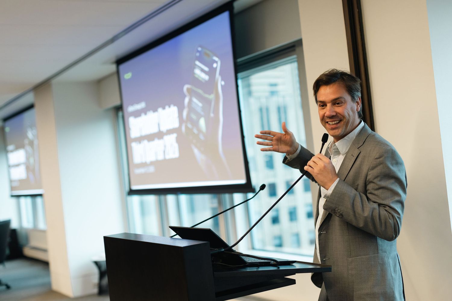 Professional speaker gestures while giving a presentation in a modern office conference room.