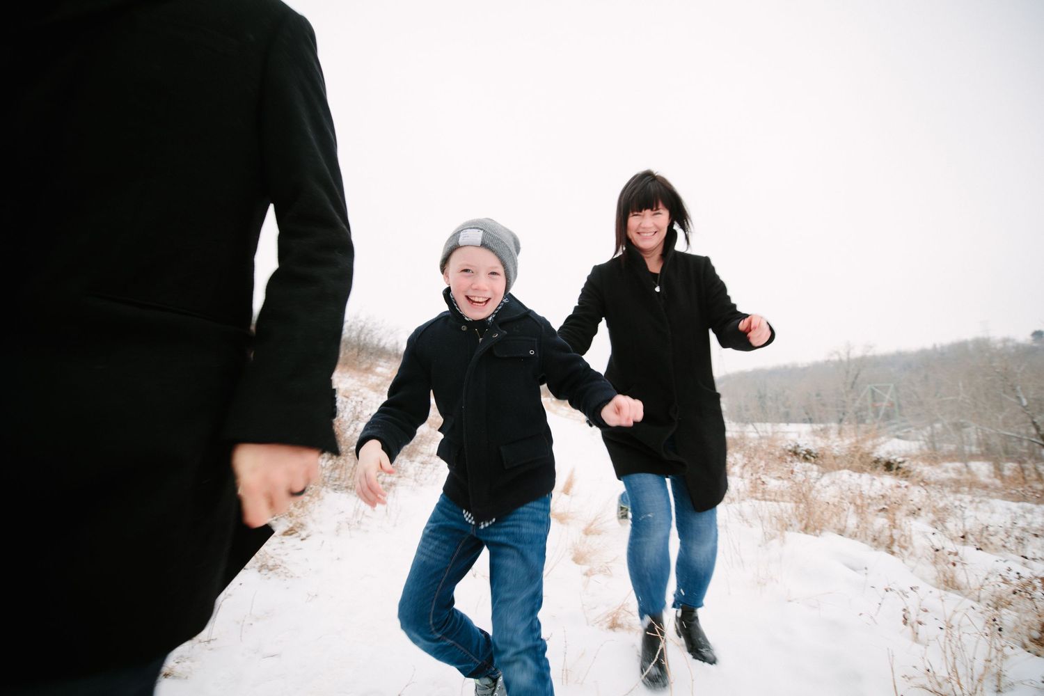 Several people chase each other joyfully across a snowy winter landscape.