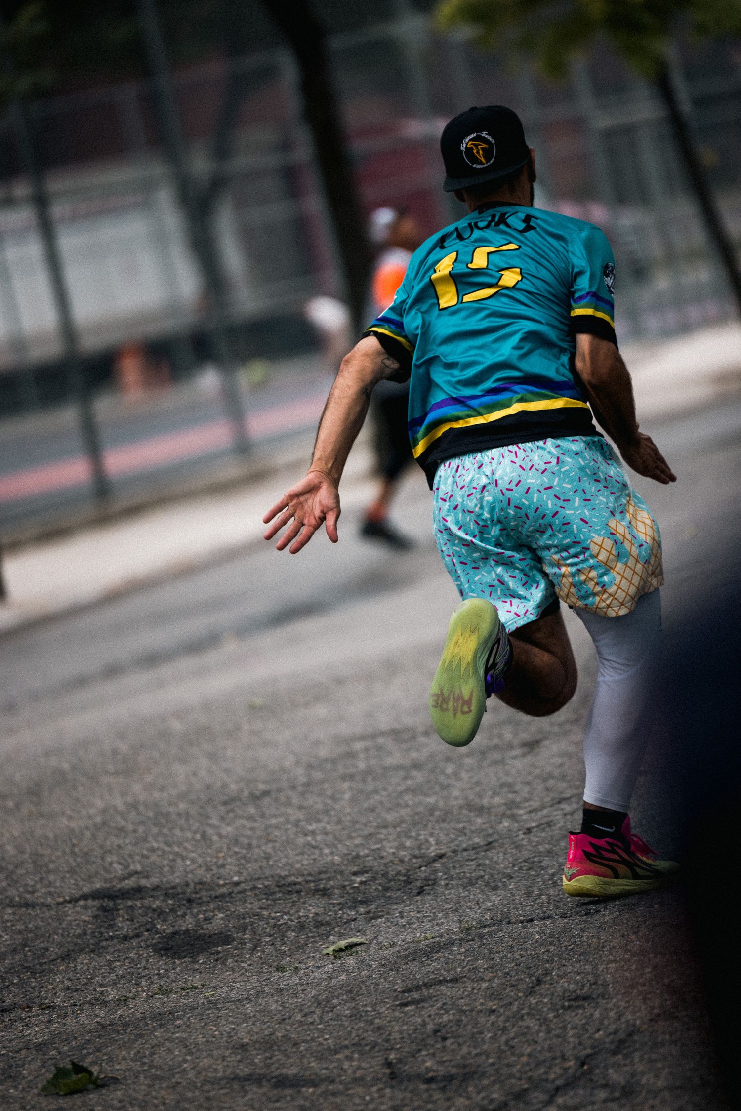 Player in blue jersey and patterned shorts jumps on an outdoor court during a sports game.