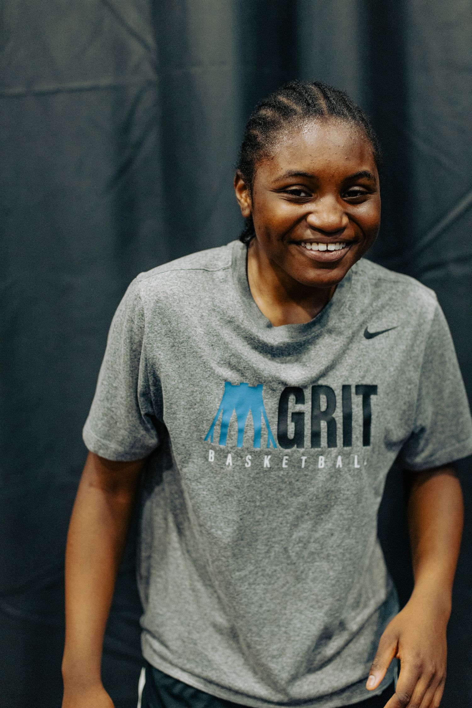 Female basketball player wearing a gray Nike t-shirt smiles during practice.