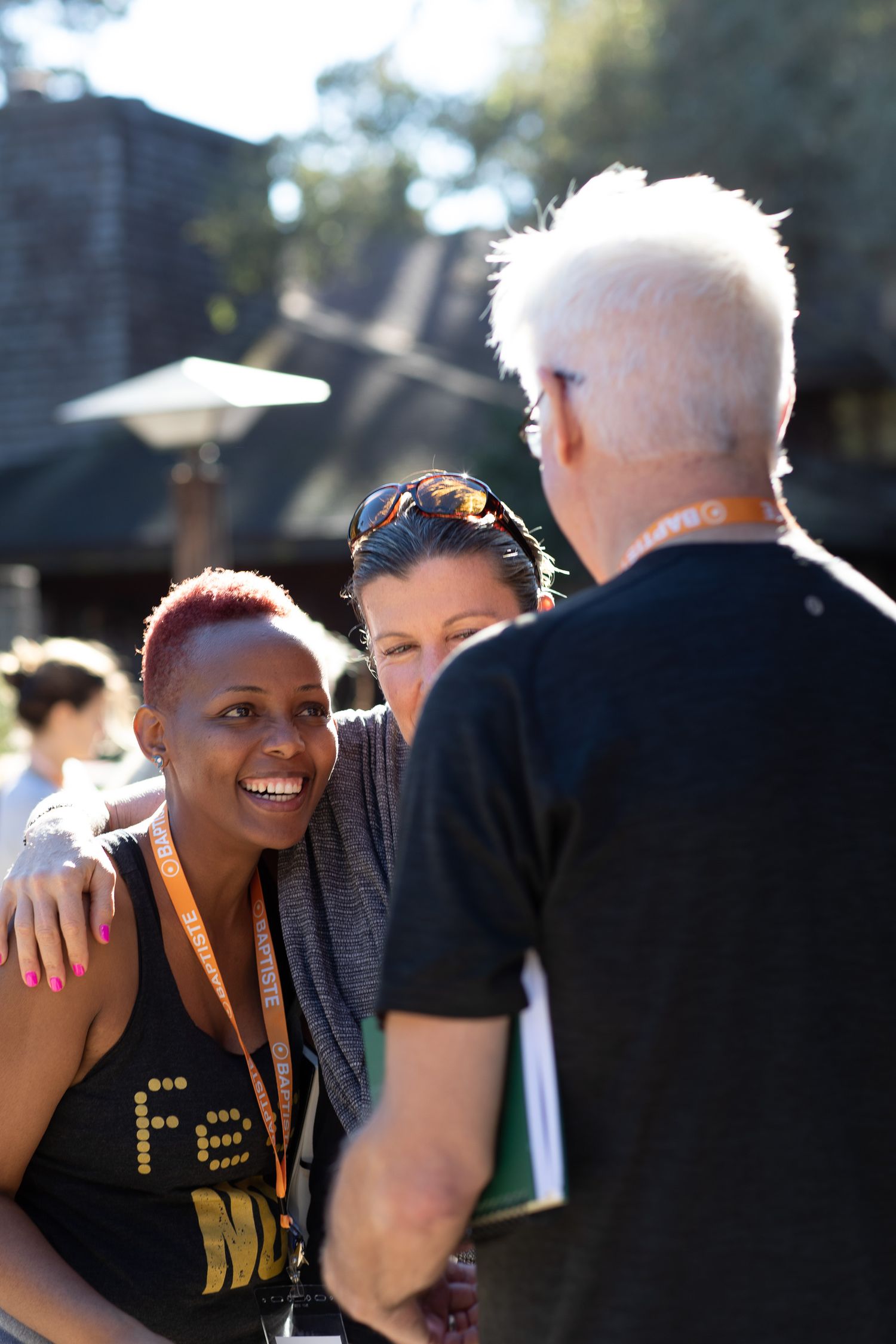 People engaging in friendly conversation and laughter at an outdoor event in casual attire.