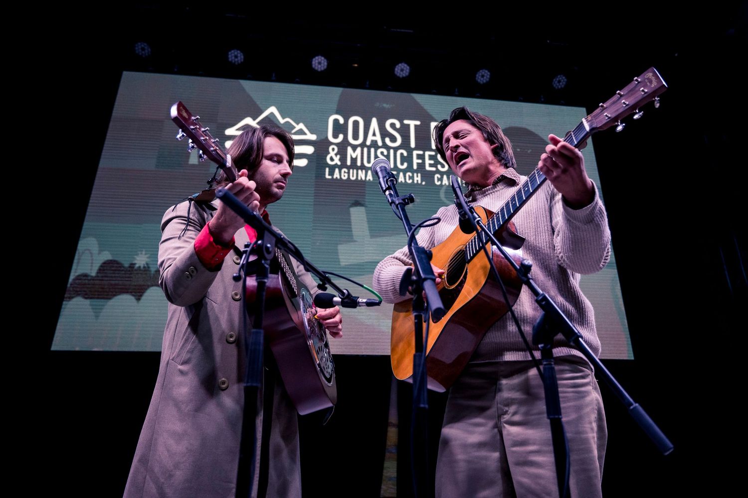 Musical performance on stage with instruments and band signage in purple lighting.