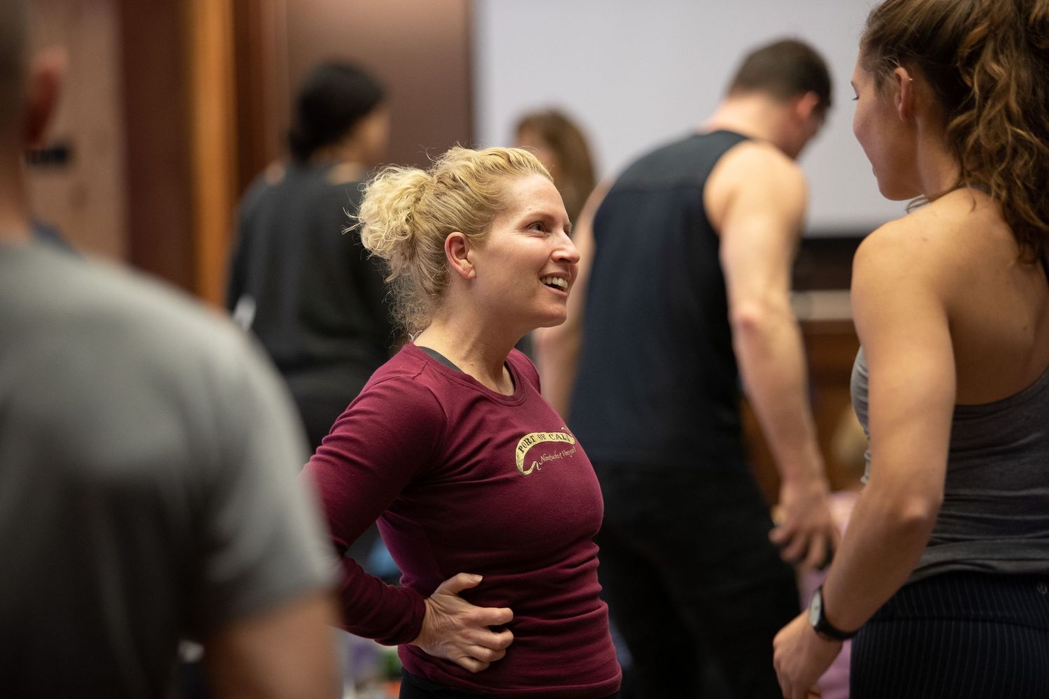 Workshop attendee in burgundy shirt smiles during conversation at fitness event.