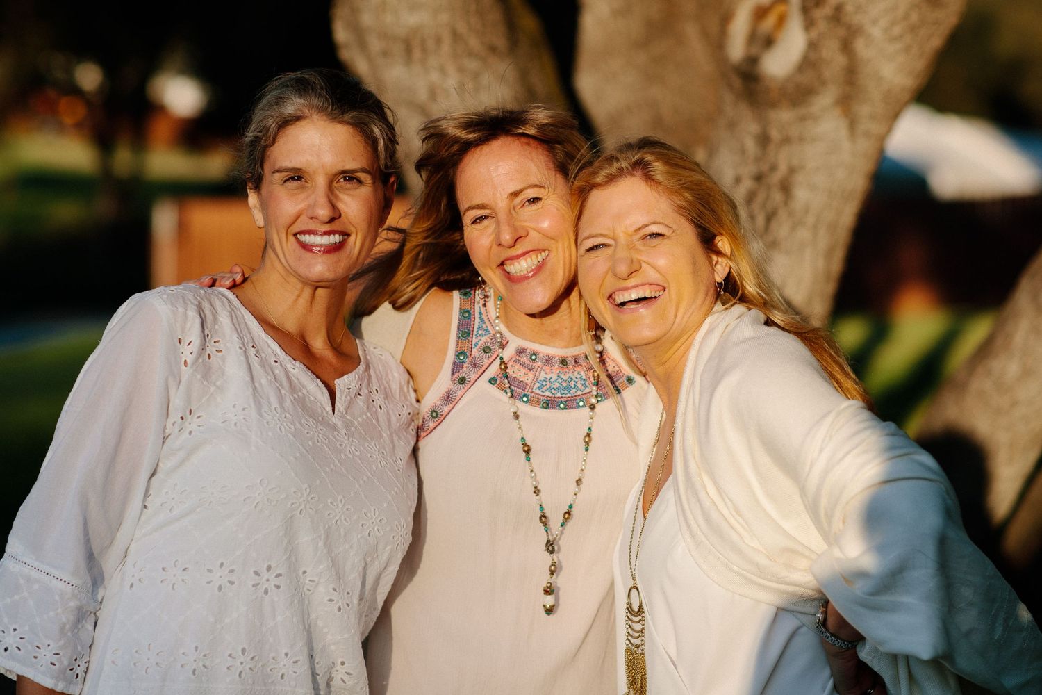 Friends in white outfits gathering outdoors for a group photo.