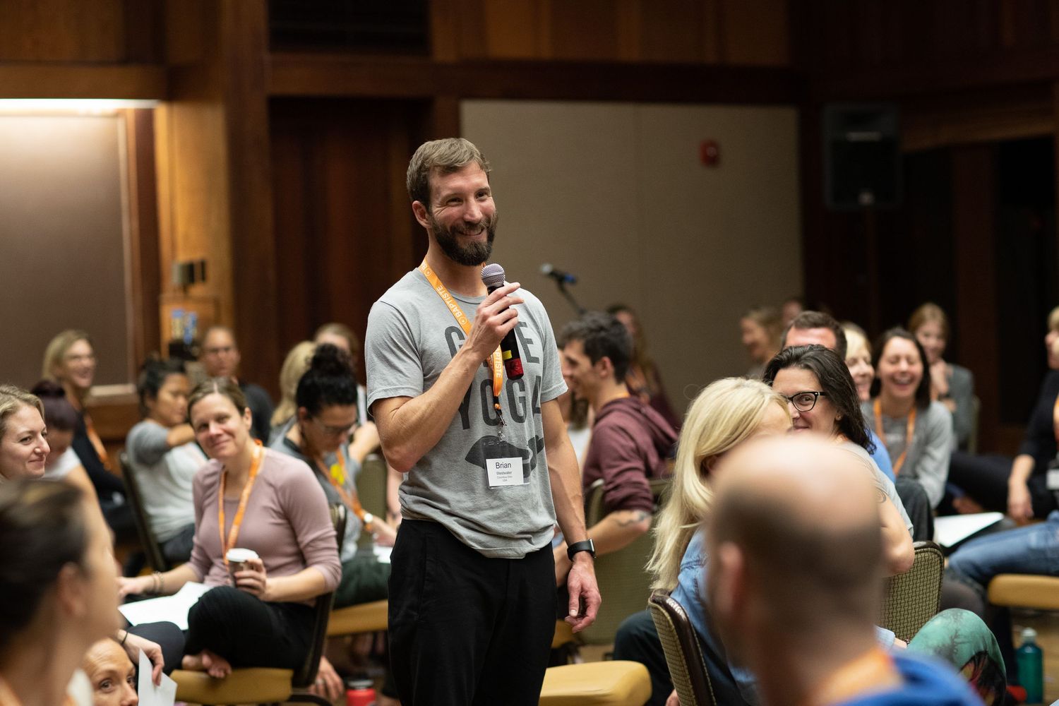 Speaker engaging with audience during a fitness workshop in wooden auditorium.