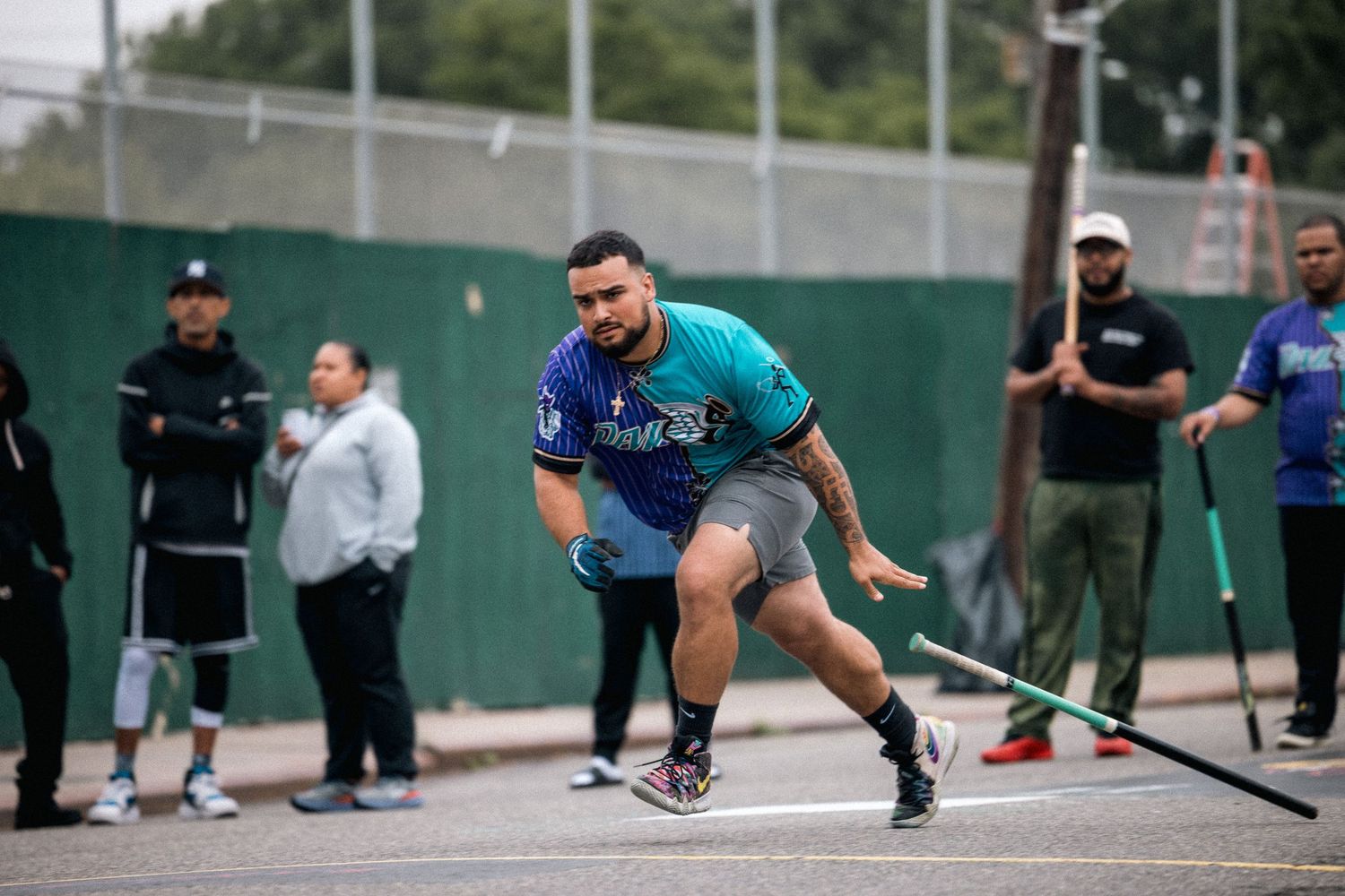Player in teal and blue uniform crouches at starting position during outdoor sporting event.