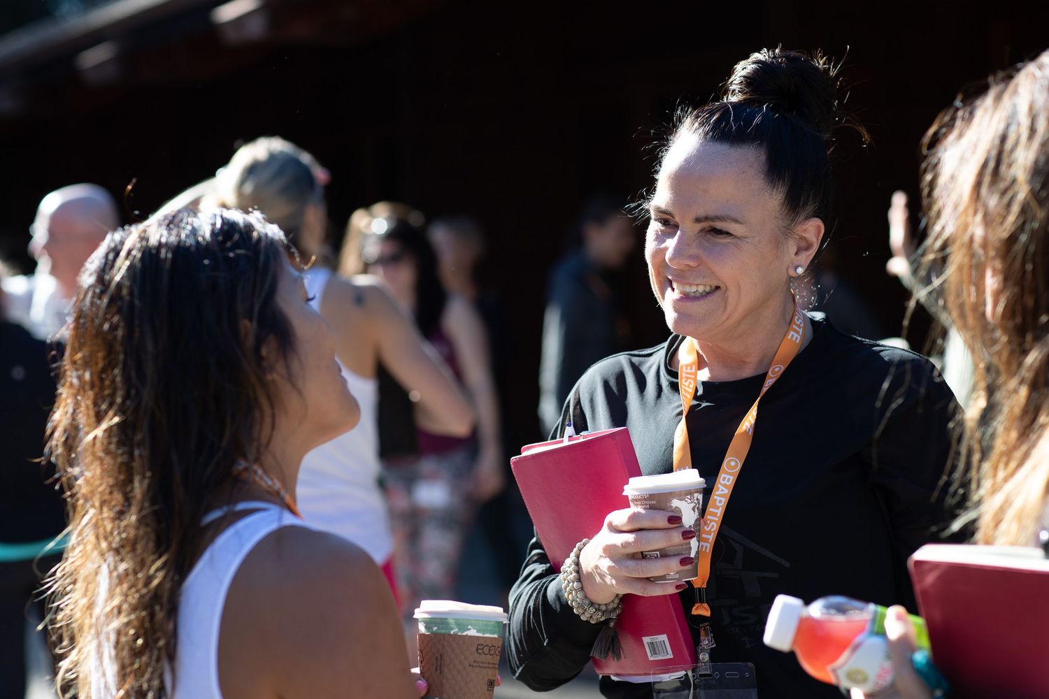 People mingling at an outdoor social gathering with drinks and conversation.