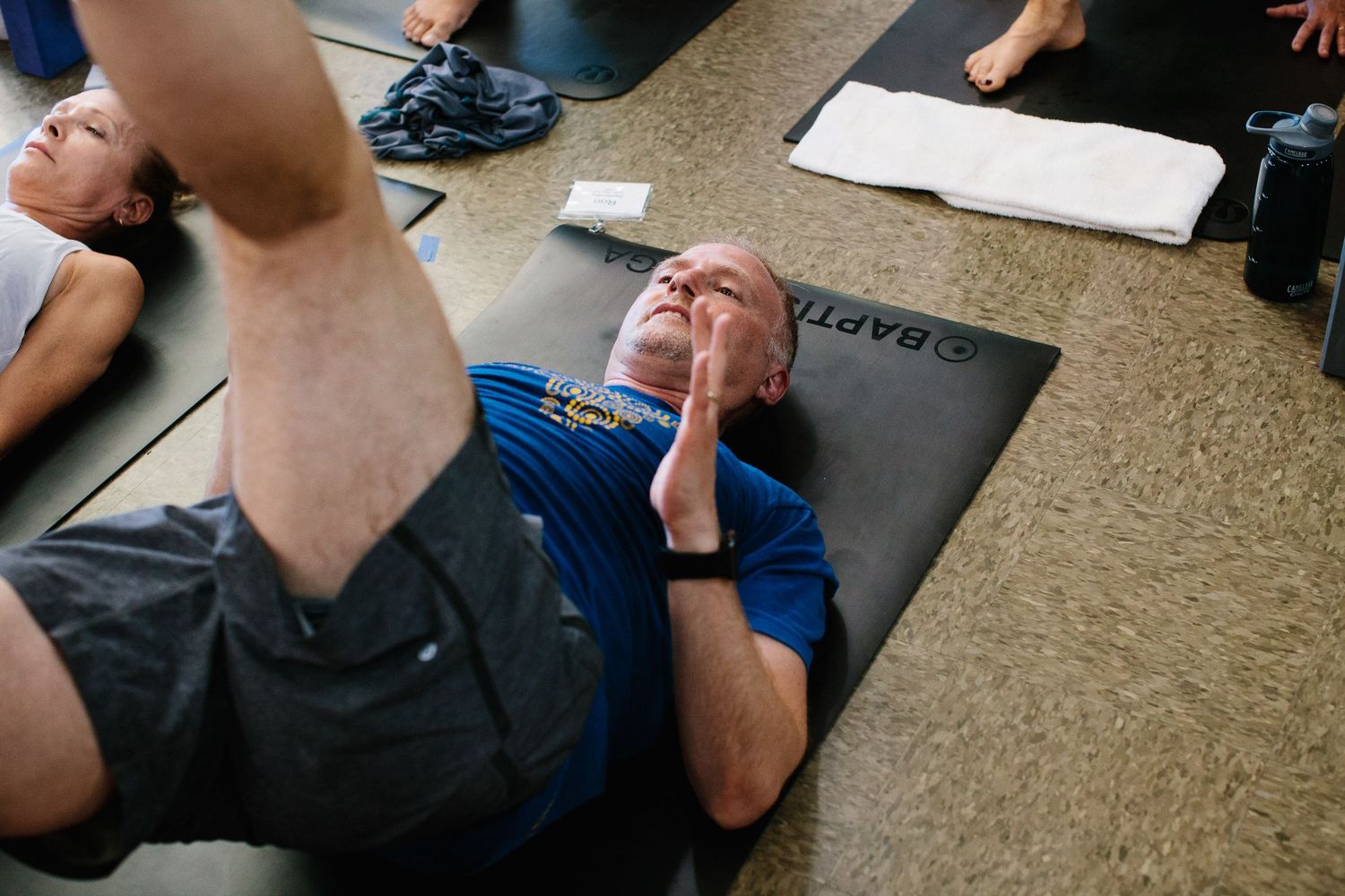 Student lying on yoga mat during floor exercise class in studio setting.