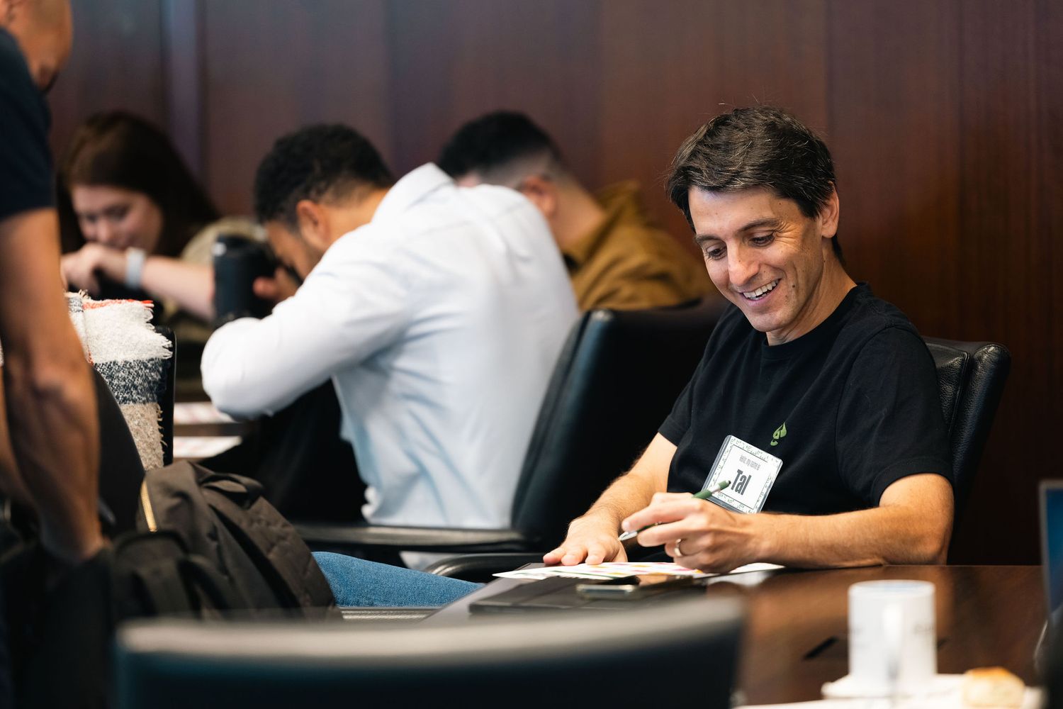 A participant takes notes during a business workshop while seated at a conference table.