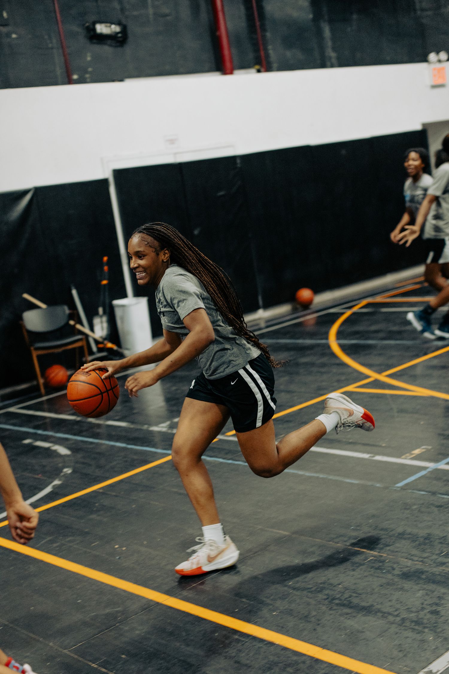 Player dribbles basketball while running on indoor court during practice session.