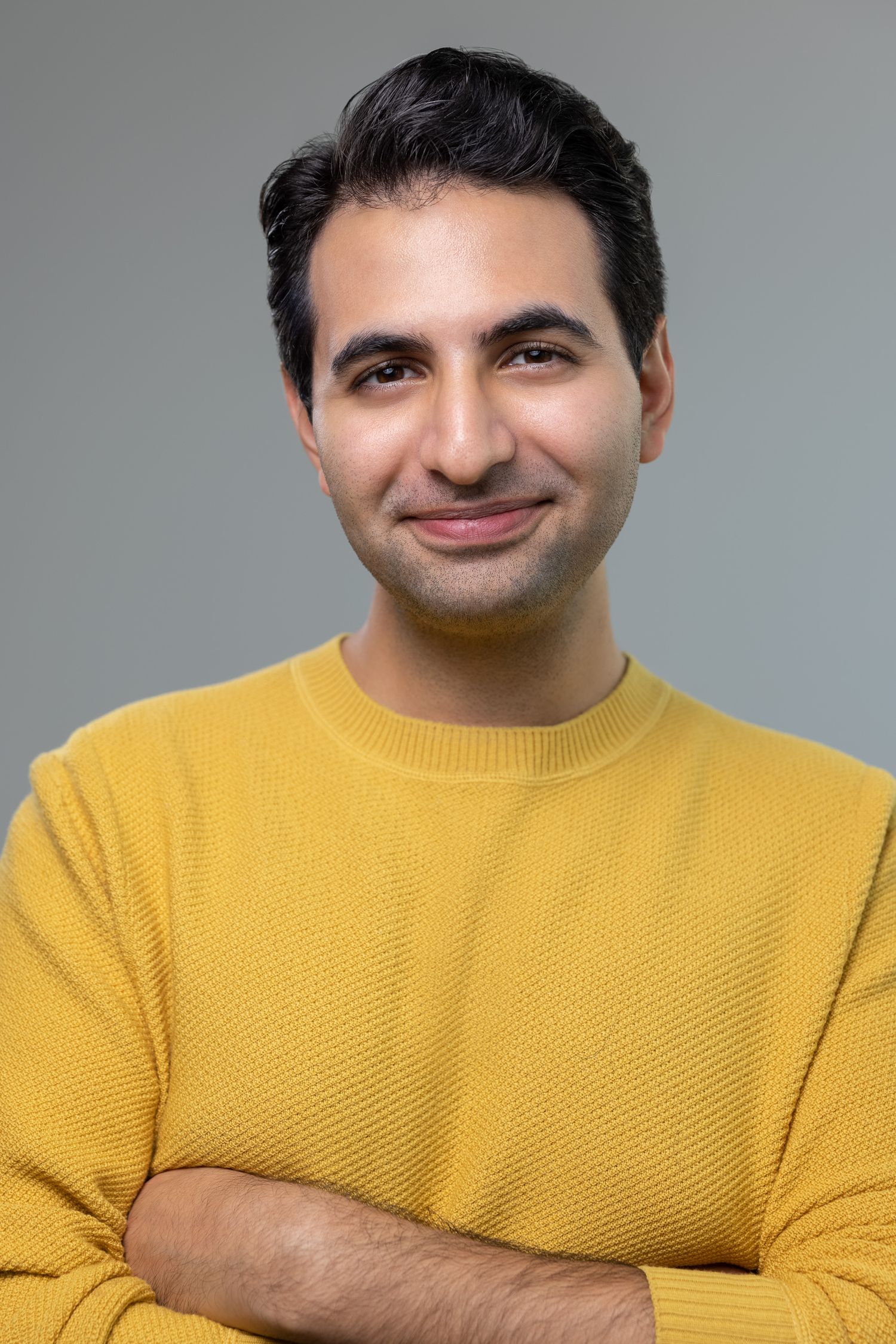 Close-up portrait of someone in a bright yellow sweater against a neutral background.