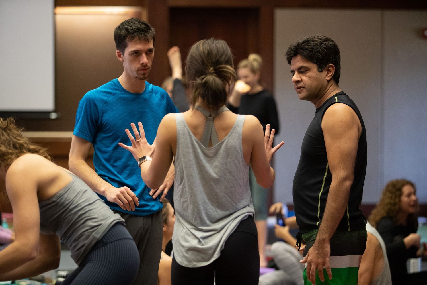 Students engage in casual conversation during a fitness or dance workshop in an indoor studio space.