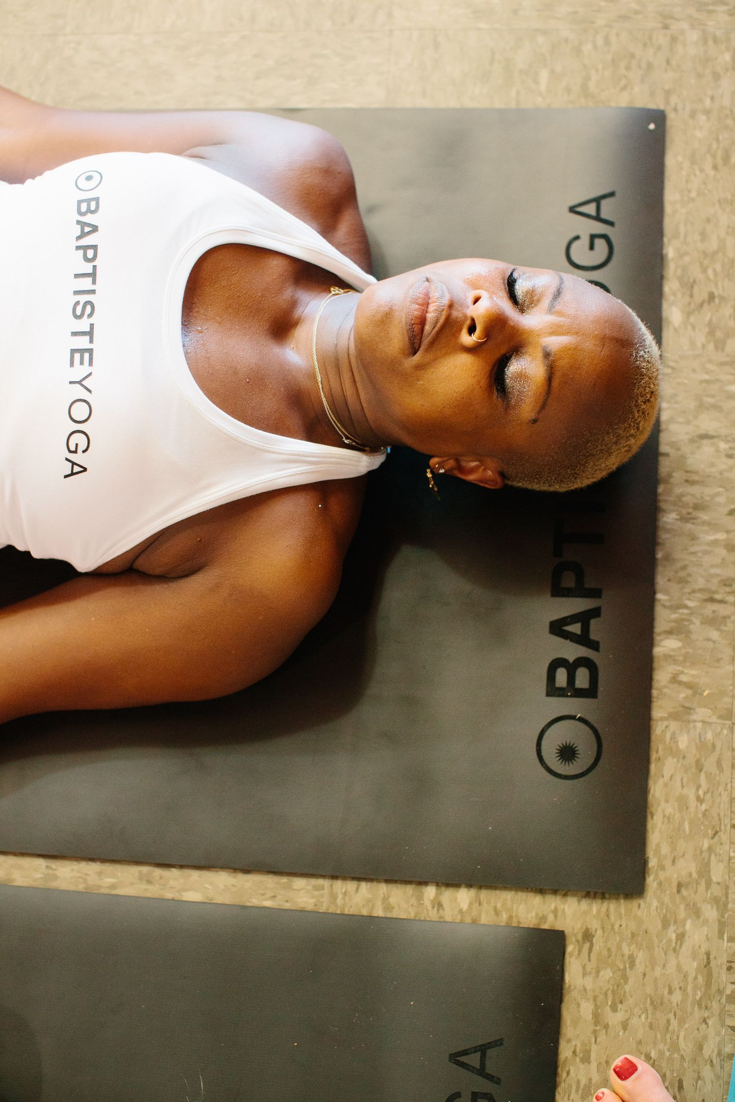 Person resting on a dark exercise mat during meditation practice.