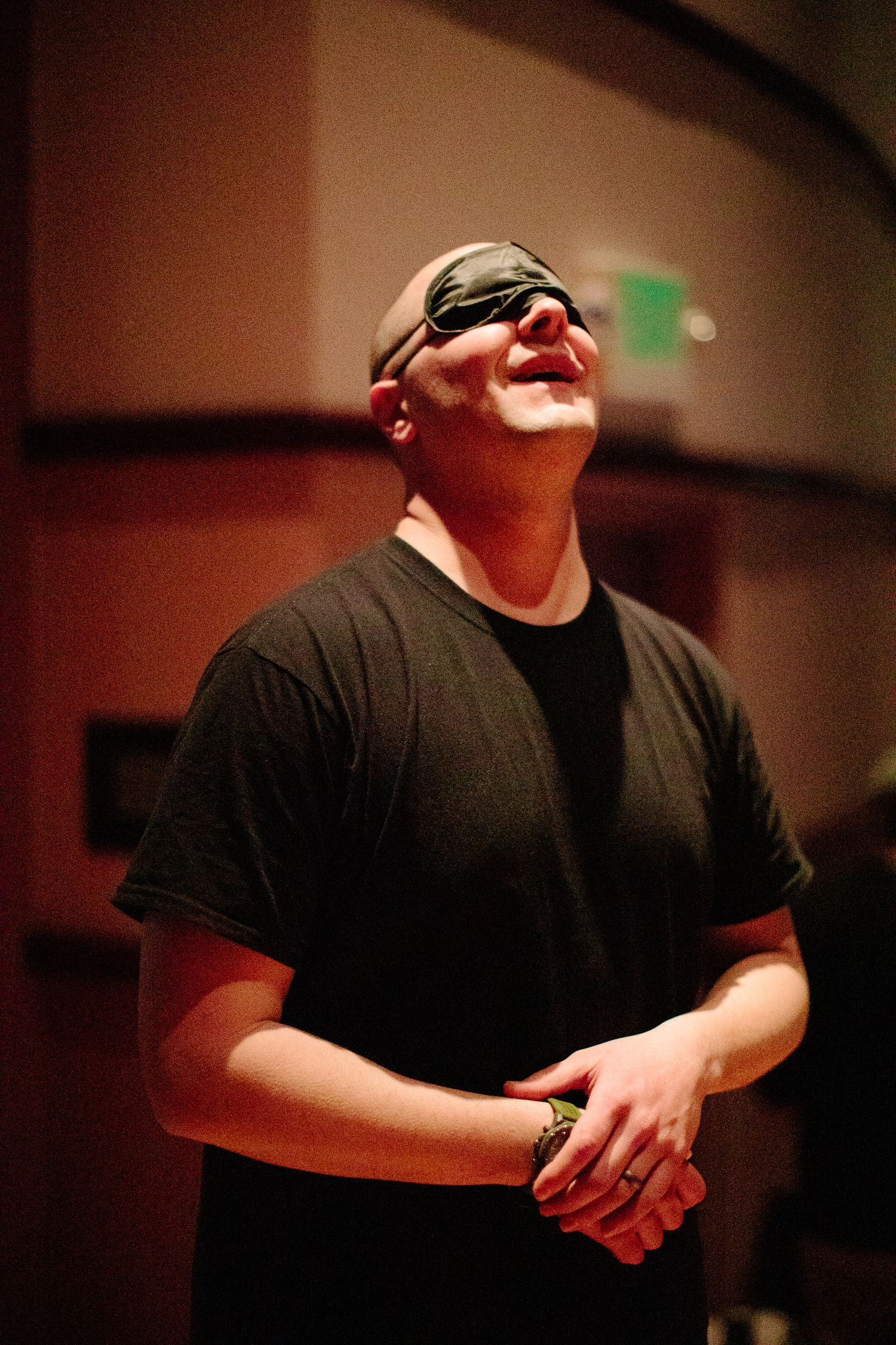 Person in black shirt demonstrating expressive movements in dimly lit setting.
