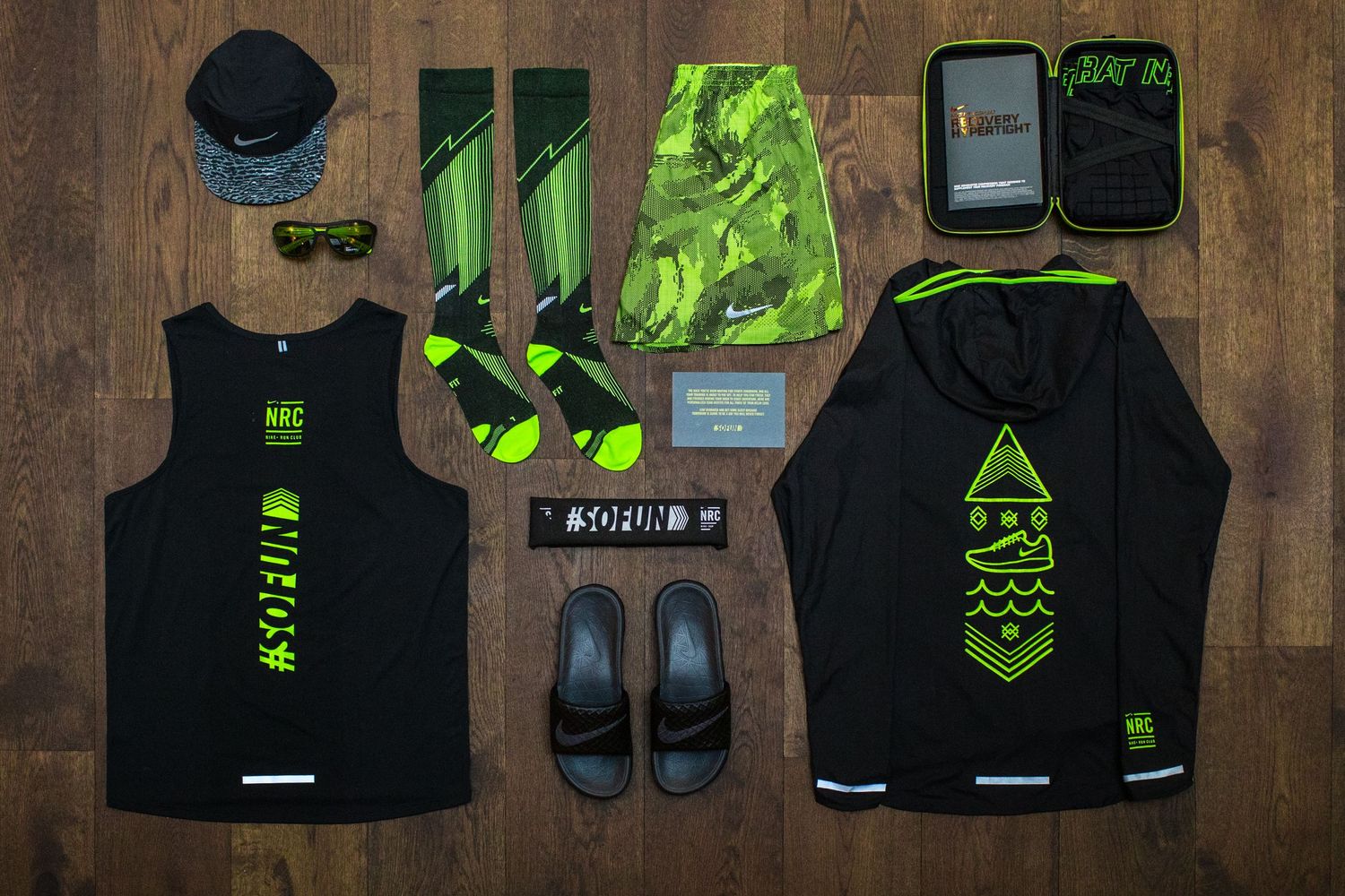 Flat lay of black and neon green athletic gear and accessories on wooden floor.