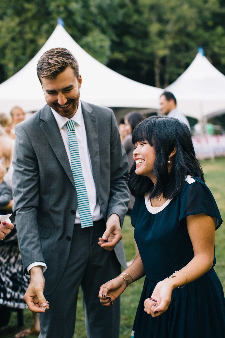 Wedding guests enjoying themselves under white outdoor reception tents.
