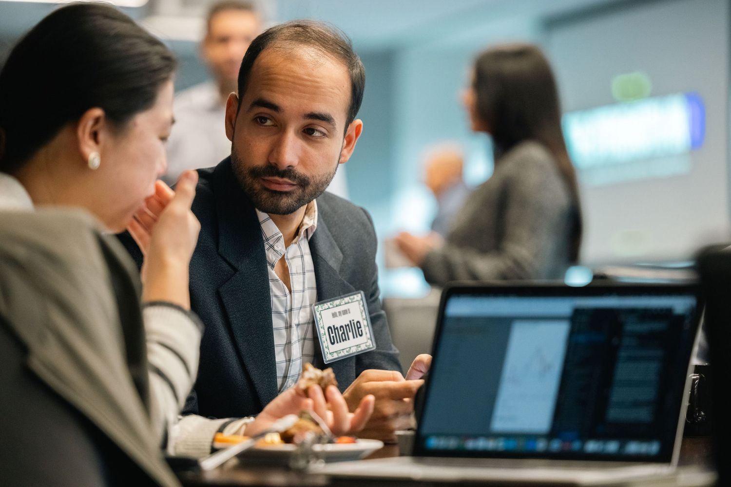 Business professionals collaborate at a desk while reviewing information on a laptop during a meeting.