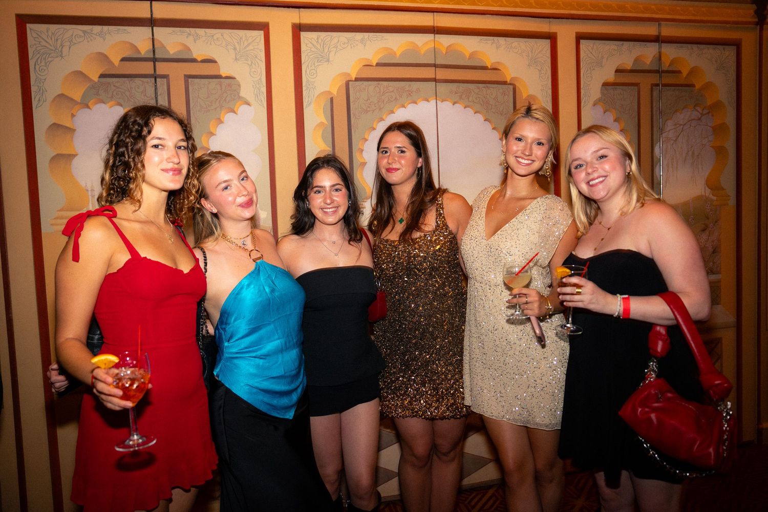 A group of friends in evening attire pose together for a photo at a formal event.