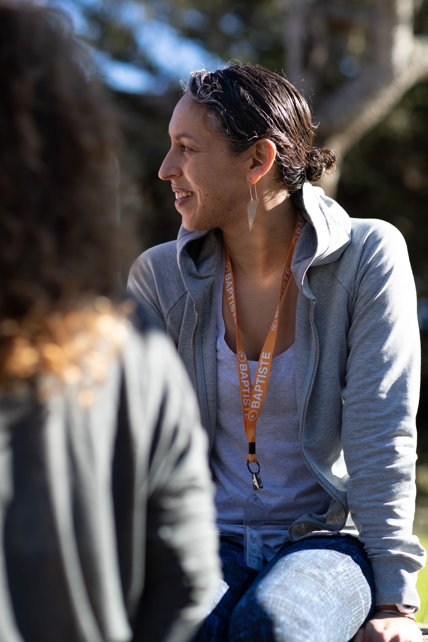 A person in a gray sweatshirt enjoys a sunny outdoor moment.