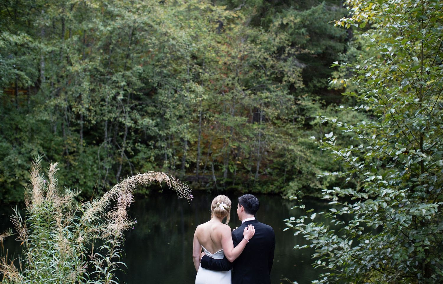 A couple shares a romantic moment in a lush garden setting with green foliage in the background.