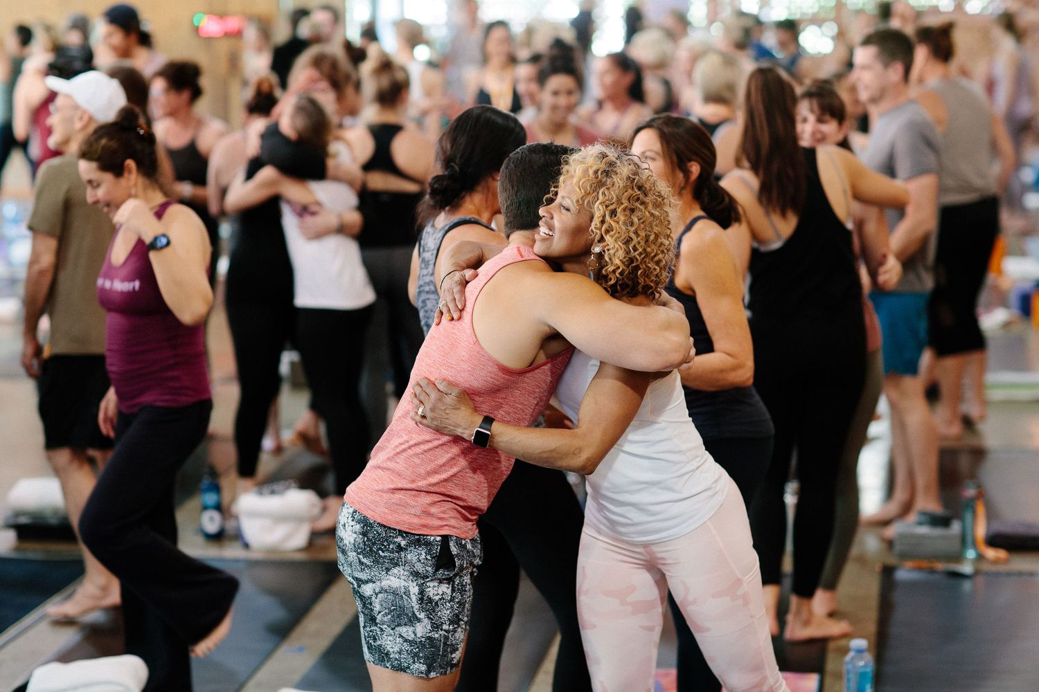Group of dancers embrace during high-energy dance class in crowded studio space.