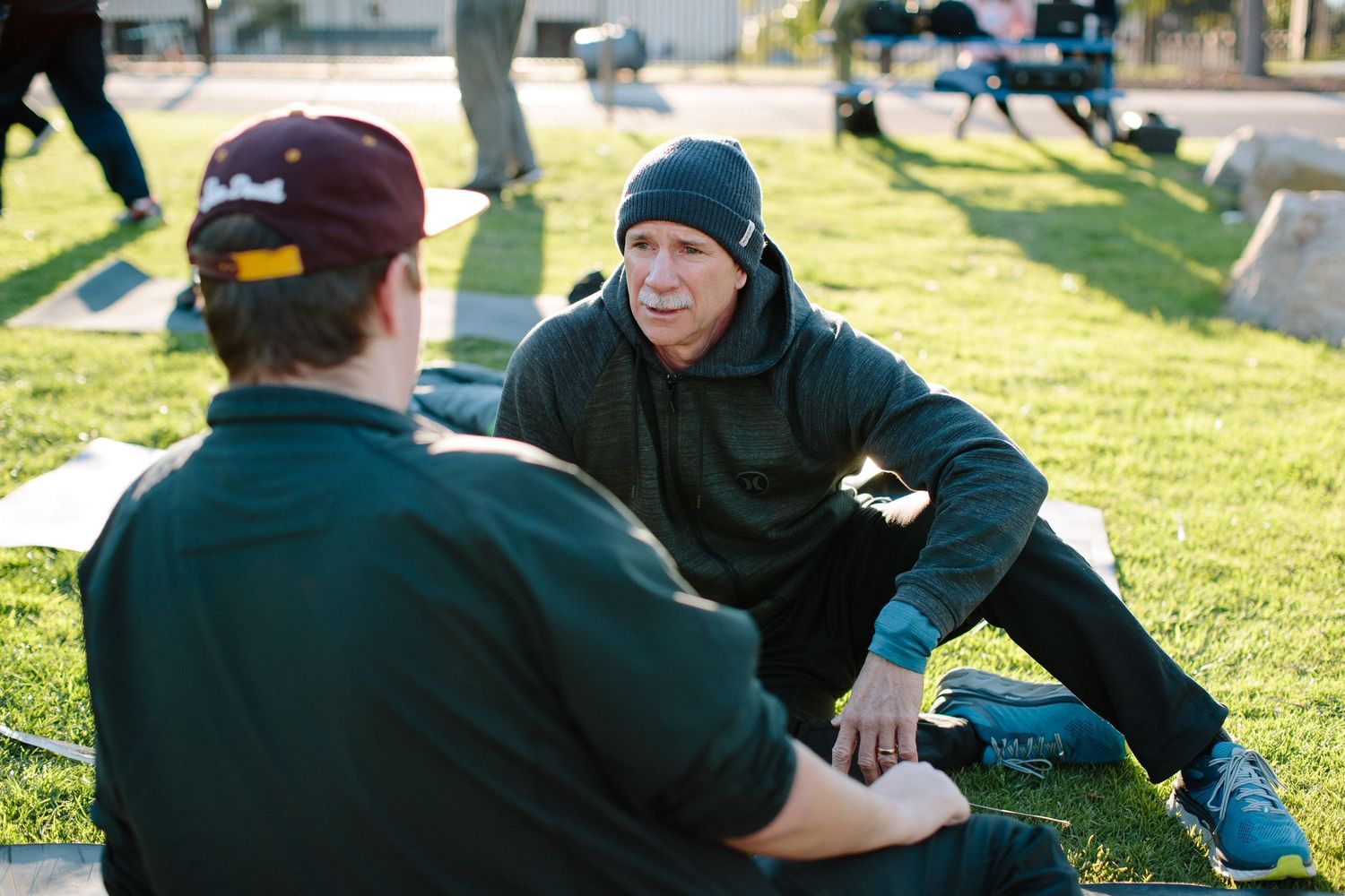 People relaxing and conversing on grass during an outdoor gathering.