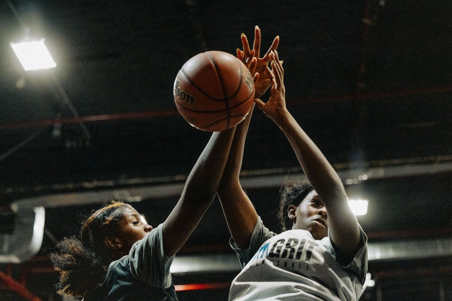 Players reaching high to contest for the basketball during an intense game moment.
