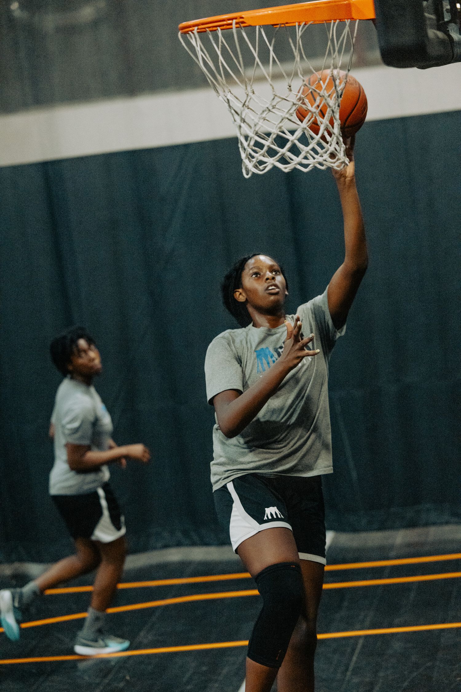 Players practicing layups and basketball skills during an indoor training session.