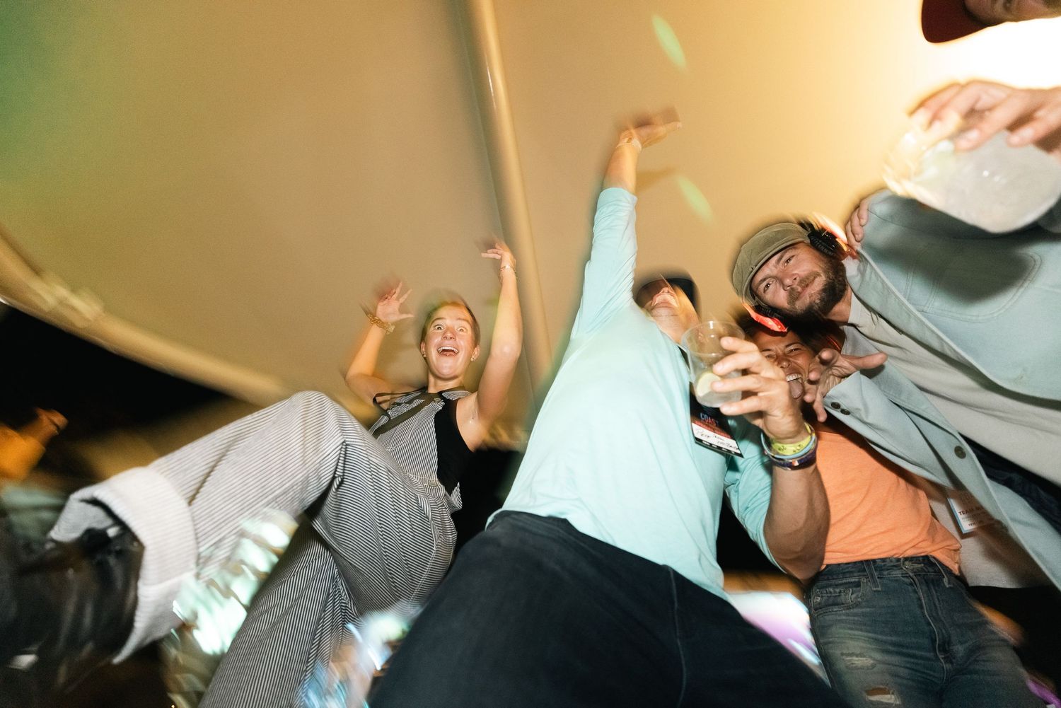 Low angle shot of energetic crowd with raised arms at indoor event.