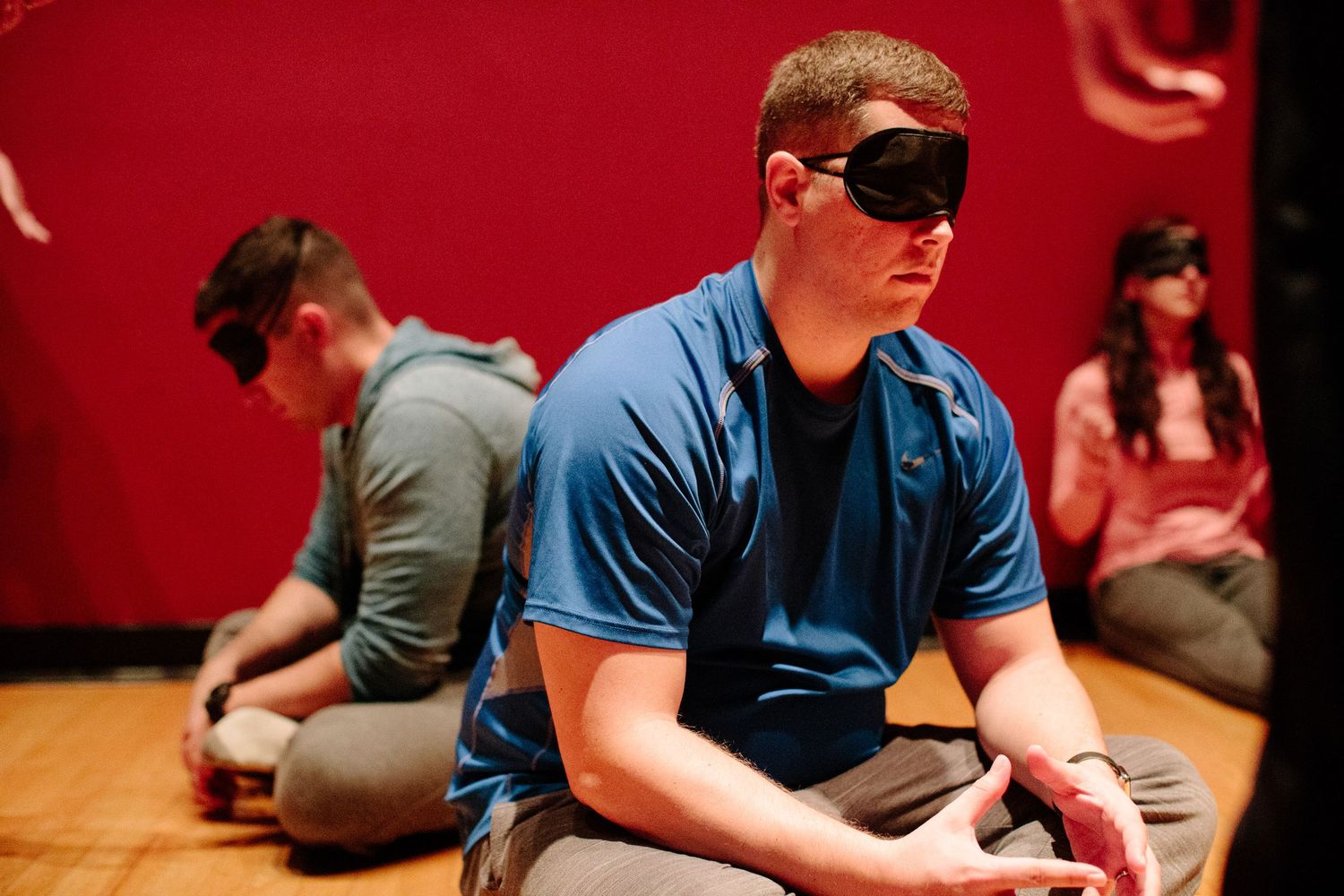 Group of people sitting in a row during an indoor training session.