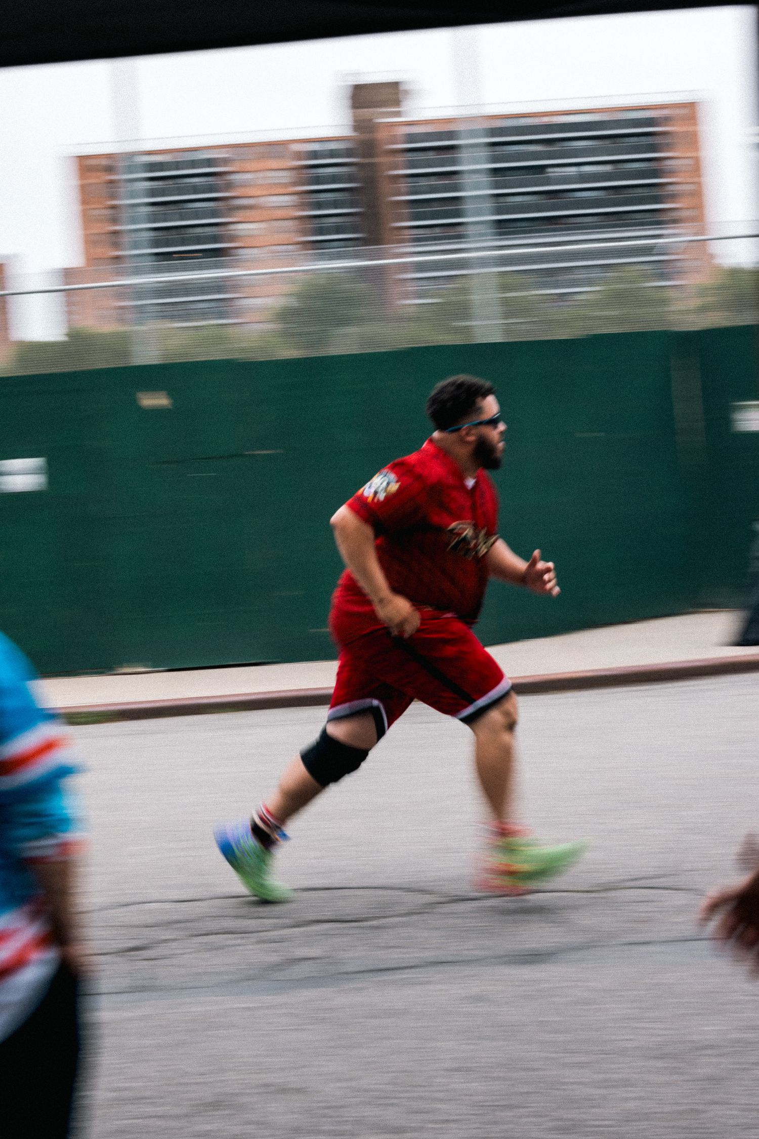 Player in red uniform running on outdoor court with motion blur effect.