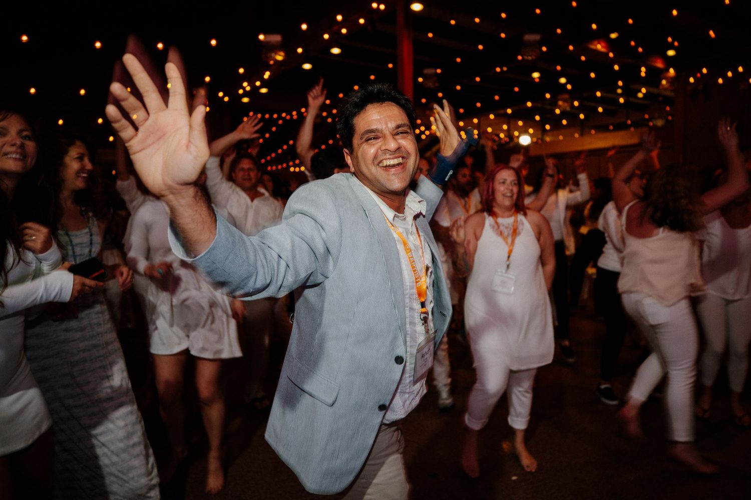 Celebration with glowing lights and people dancing in white attire at a nighttime event.