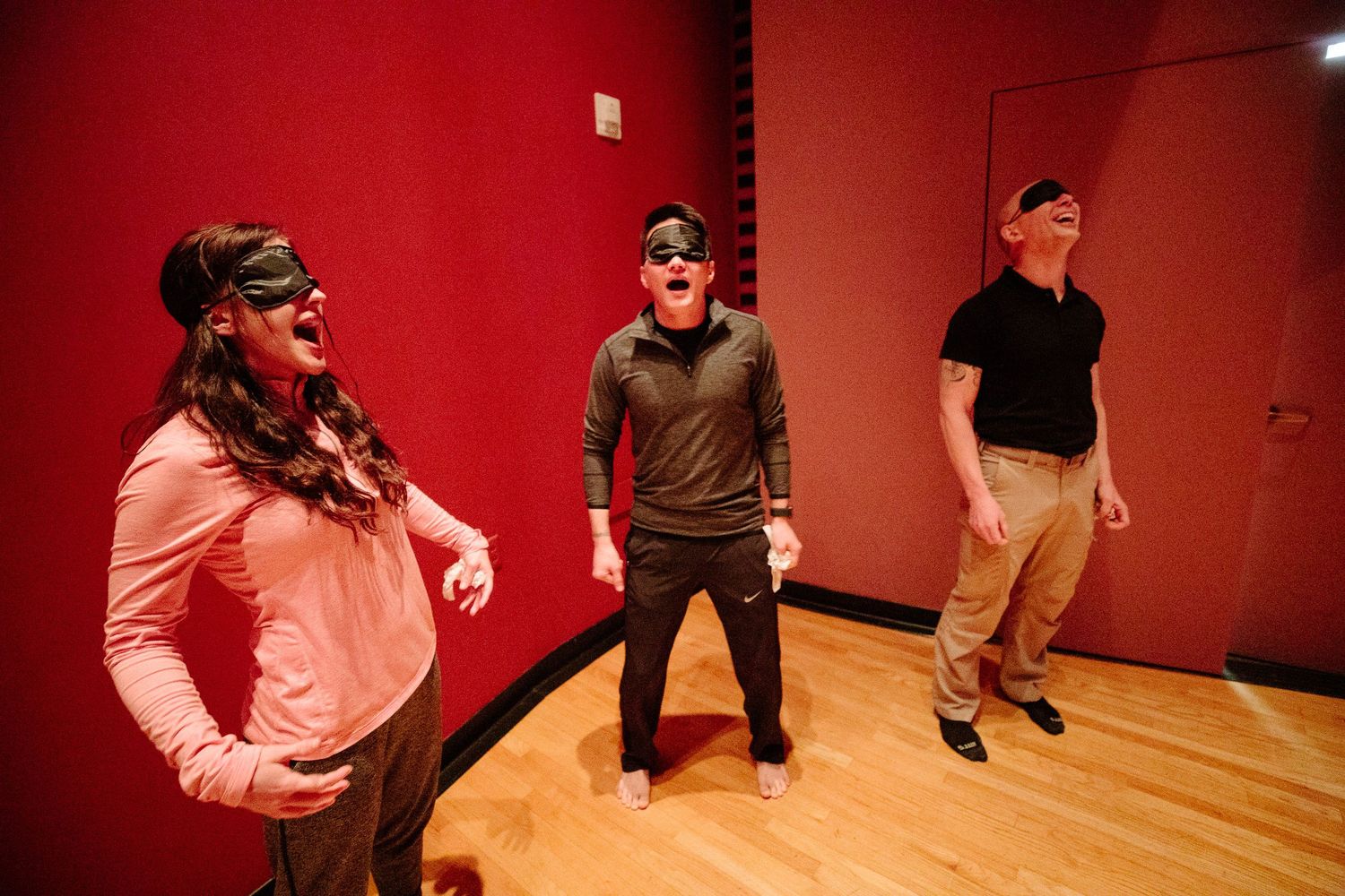 Group participants engage in movement activities in a studio space with red walls.