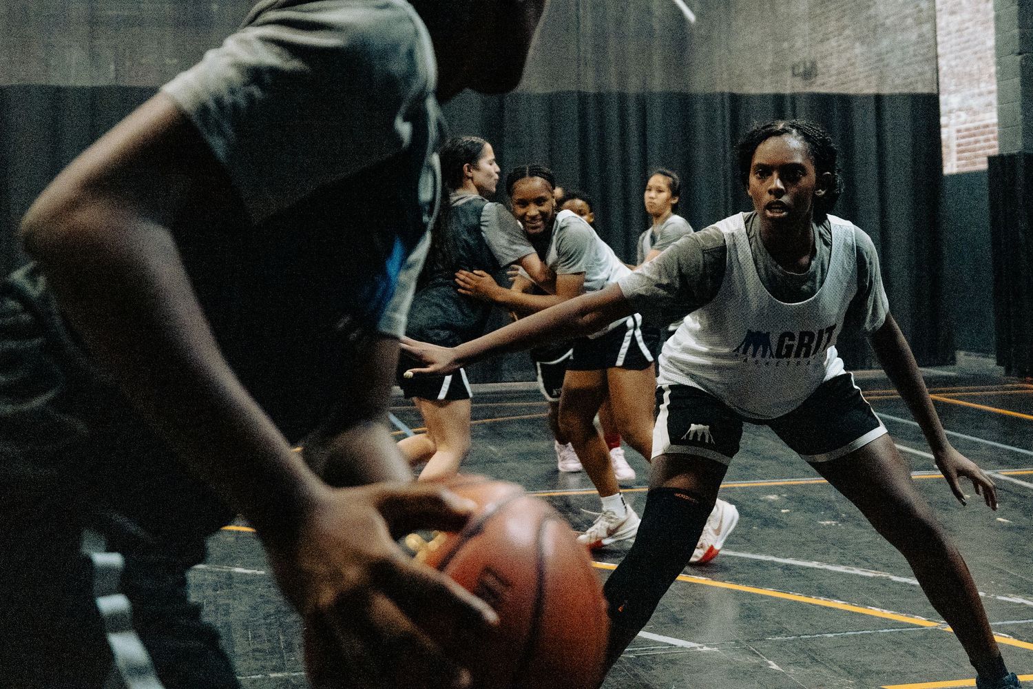 Basketball players compete intensely for the ball during an indoor pickup game at a gymnasium.