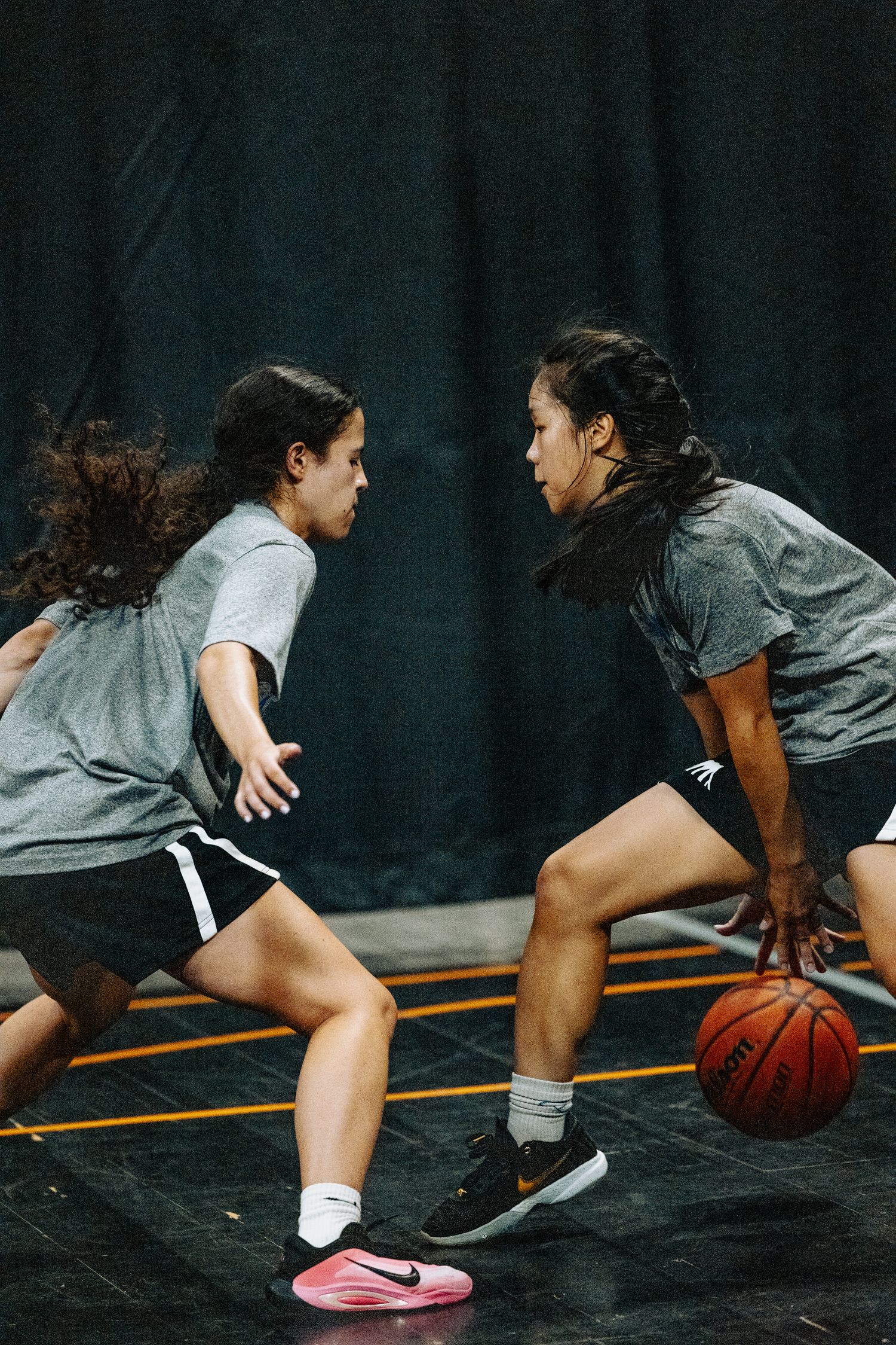 Two basketball players engage in an intense one-on-one match on an indoor court.