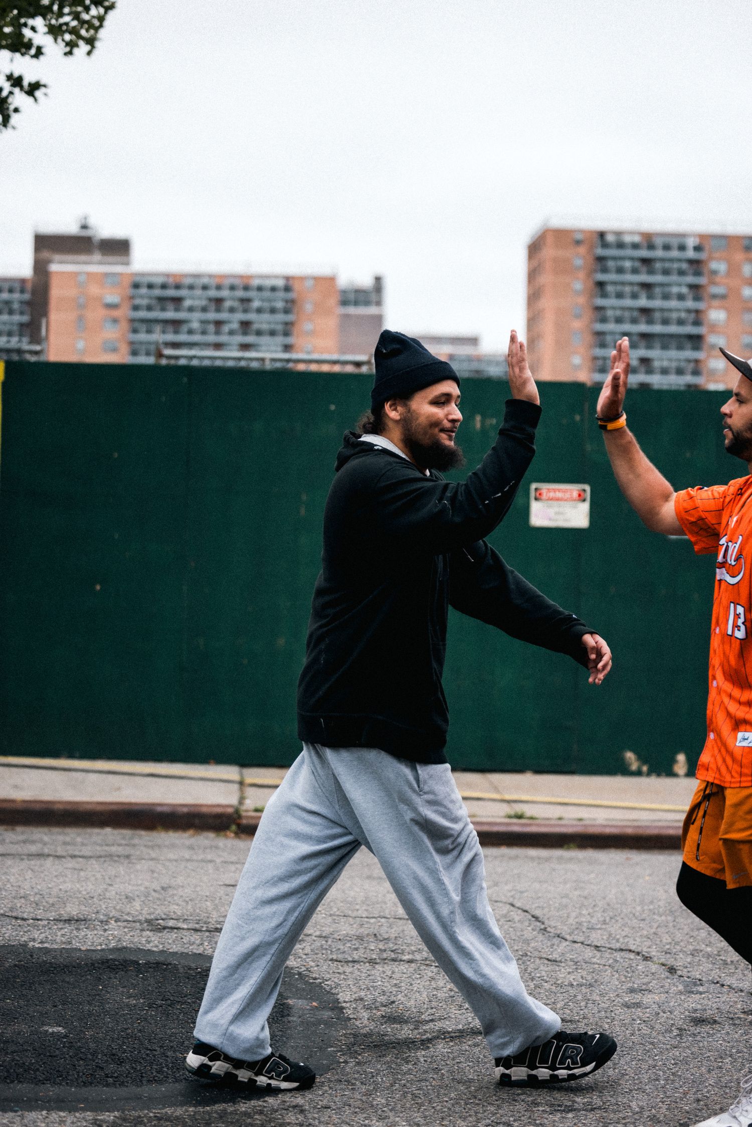 Two players high-fiving during a casual outdoor game with apartment buildings in background.