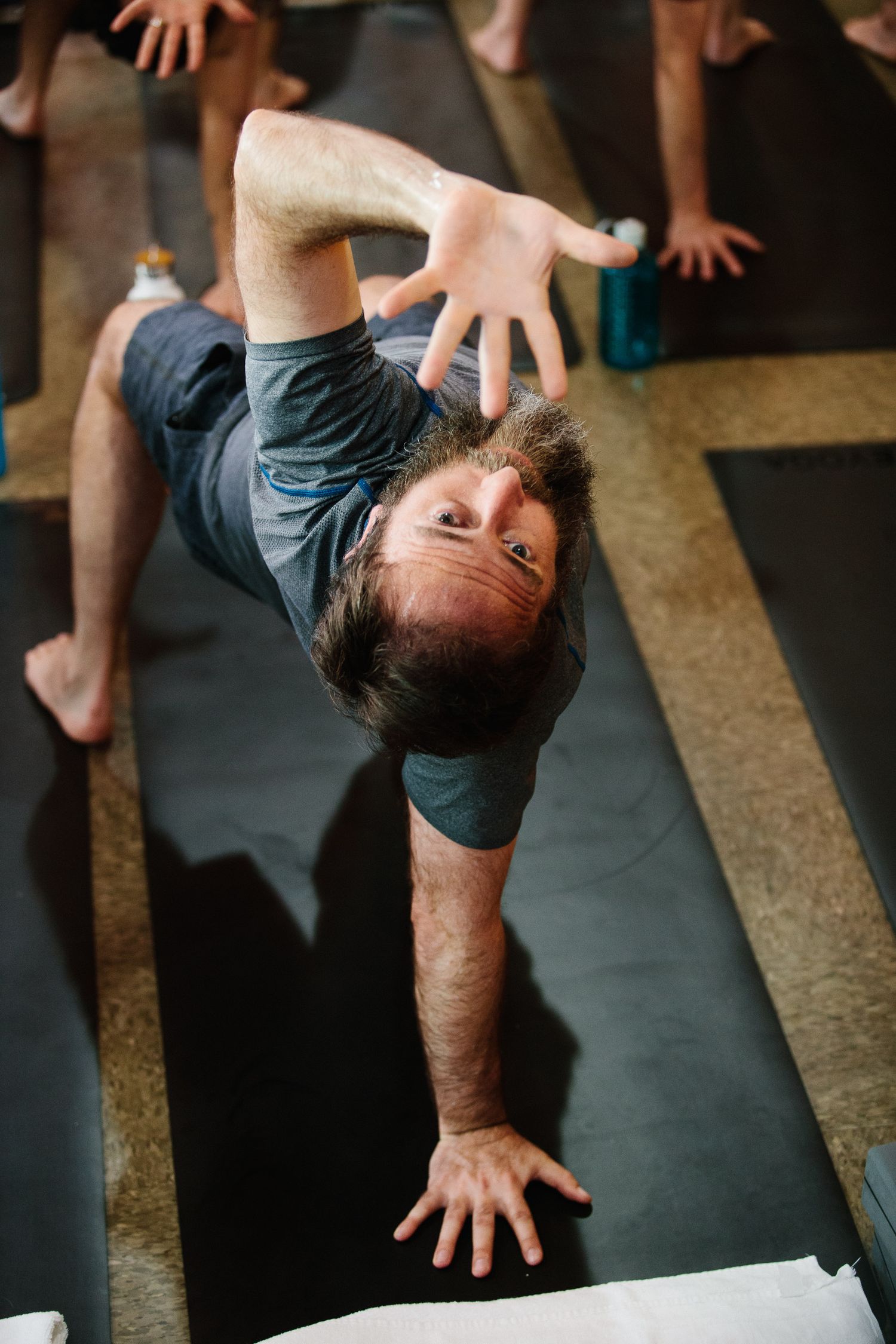 Student performing advanced yoga pose on dark exercise mat.