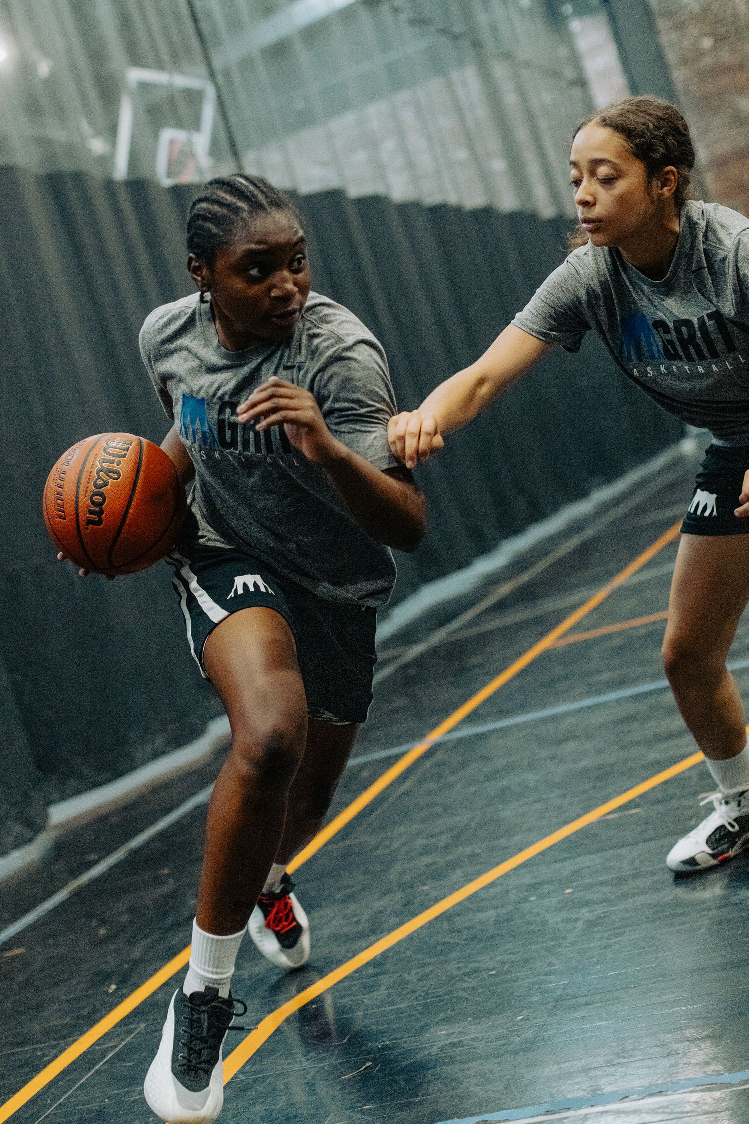 Basketball players demonstrate defensive moves during an indoor practice session.