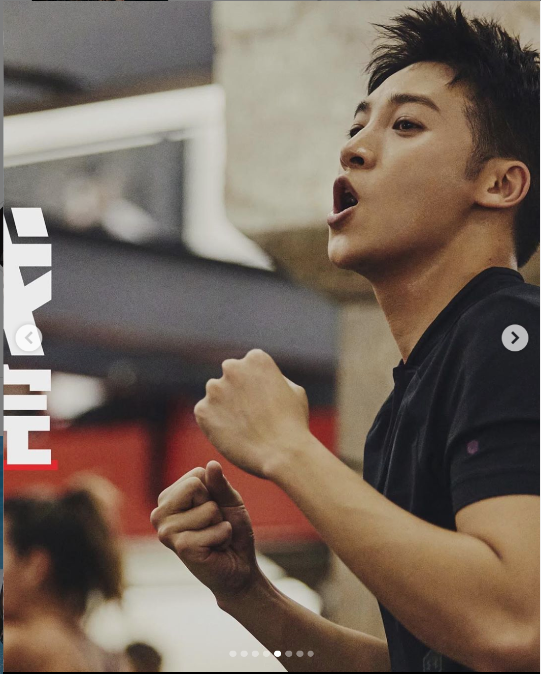 A performer in black attire sings passionately with clenched fists raised during an energetic performance.