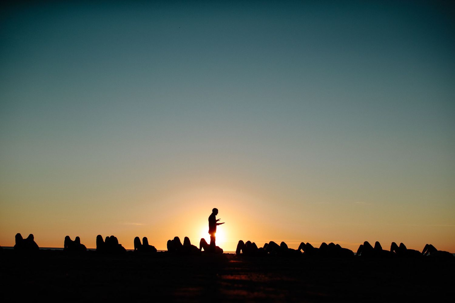 Silhouette of audience members watching performance at sunset.