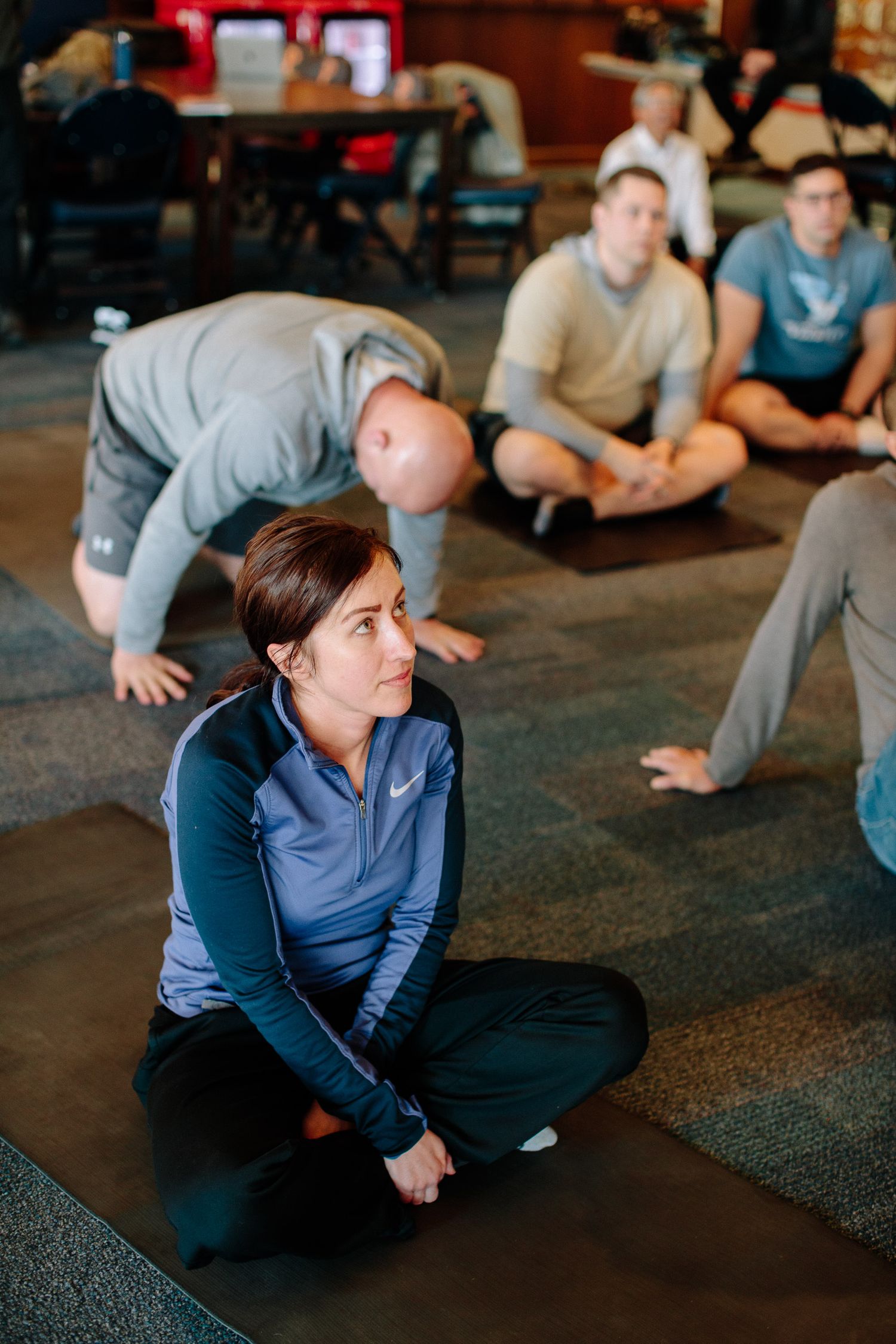Training participants sitting on floor during interactive workshop session in casual setting.