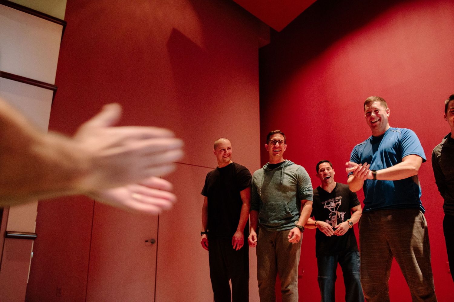 People practicing movement exercises in a room with red walls.